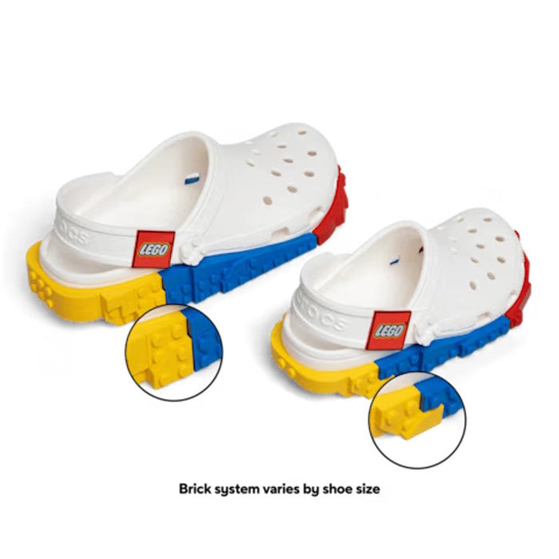 The Crocs Adults LEGO® Creativity Clog White Unisex features a white slip-on design with colorful LEGO brick attachments on the sides and soles. Bright red, yellow, and blue interlocking LEGO bricks are showcased on the sole, while classic Crocs Comfort e