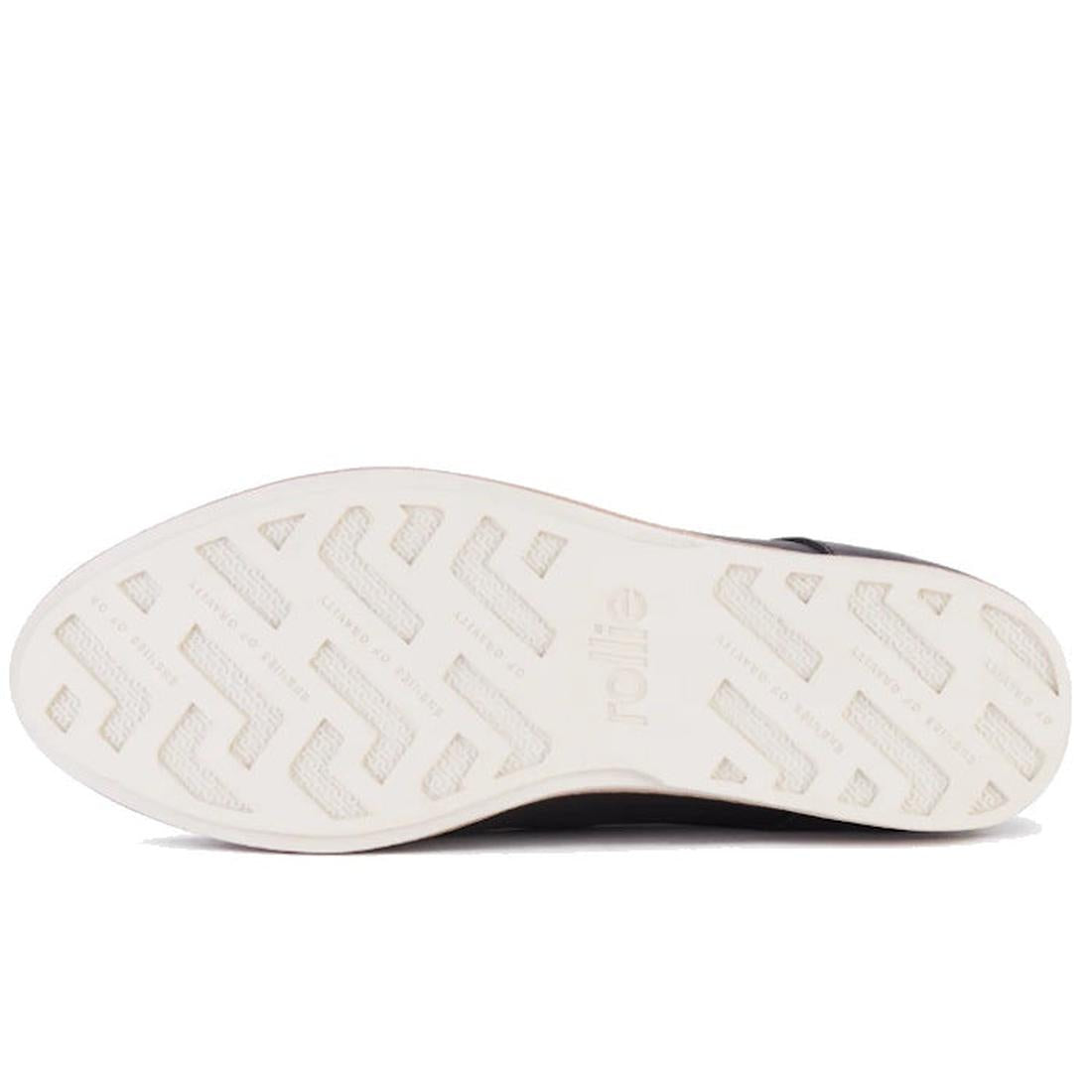 The image shows the white textured sole of the Rollie Womens Derby Black Leather Brogue Shoe, featuring "rollie" embossed in the center and a zigzag tread for grip. The shoe is viewed from below, highlighting its sneaker-like comfort., 9339554248271, 9339