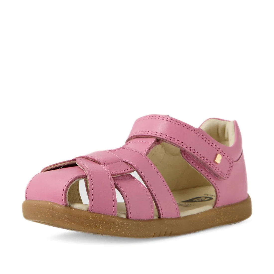 The Bobux IWalk Skip Twist Sandal in Cashmere Rose Pink is a closed-heel, open-toe toddler sandal featuring a Velcro strap. Designed with a flat light brown sole and an upper constructed from multiple leather straps for breathability, these sandals are pe