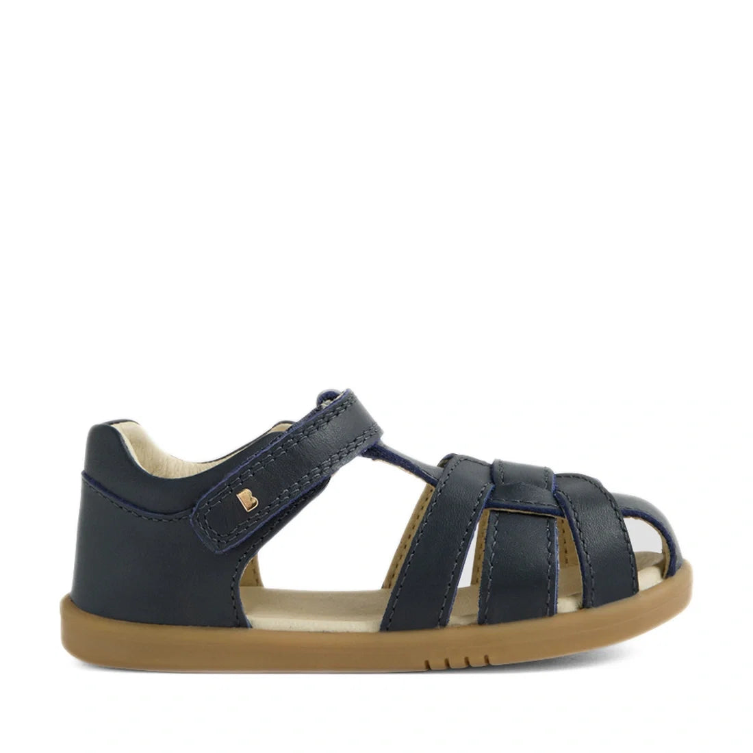 The Bobux IWalk Skip Twist Sandal Navy Closed Toe Toddlers is a navy blue sandal for children featuring a tan rubber sole and an open toe, with a secure Velcro strap at the ankle. Designed as breathable kids’ shoes, this sandal includes multiple straps ac