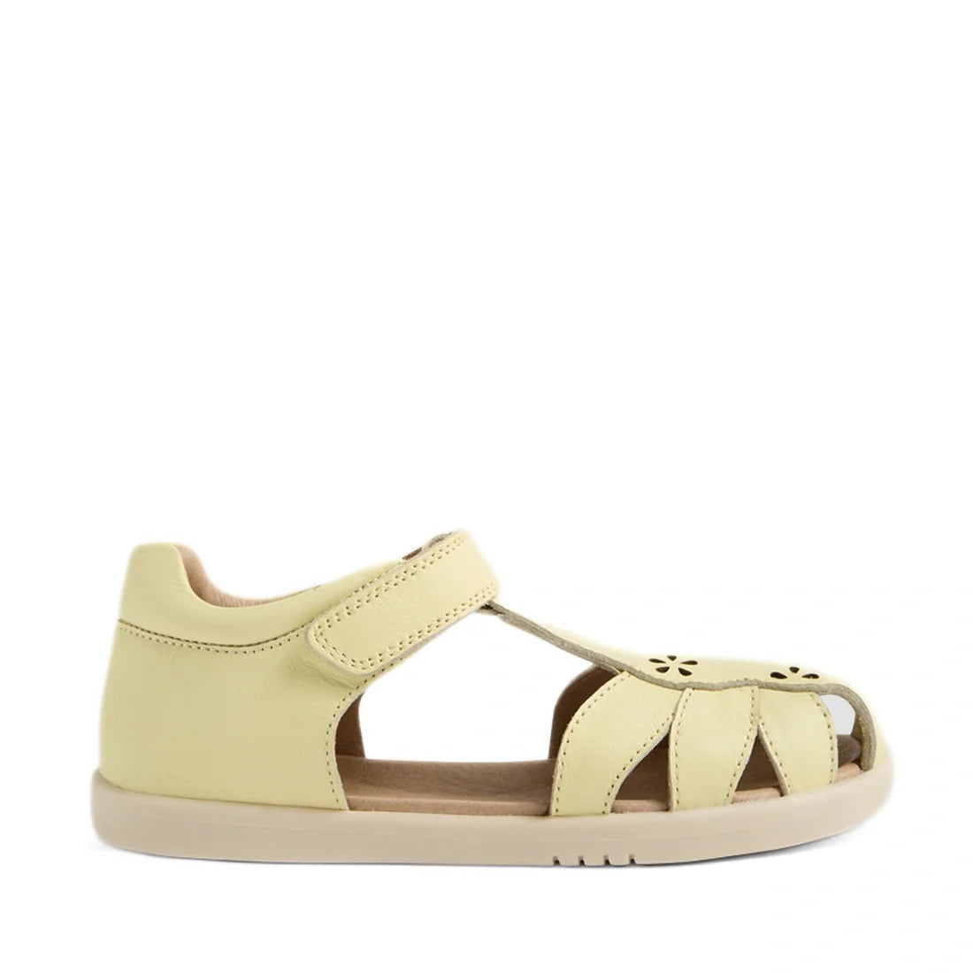 A single Bobux Kid+ Plus KP Holly Wax Yellow Closed Toe Sandal for children features a pale yellow leather design with a closed heel, open toe, cut-out sides, floral cutout accents on the toe, and a convenient velcro strap—making it the perfect choice for