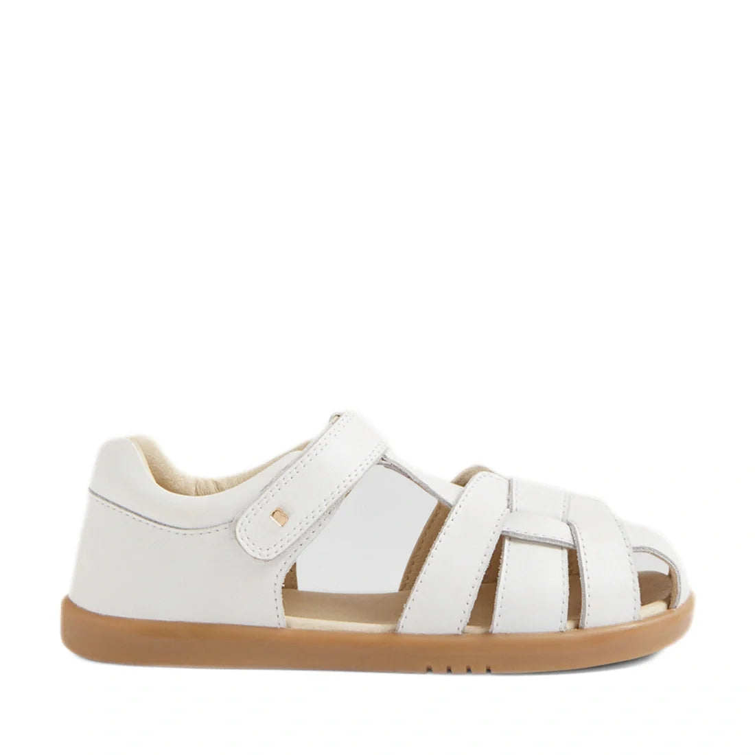 The Bobux Kids Plus KP Skip Twist White Closed Toe Sandal features a white leather upper, closed heel, open toe, tan rubber sole, and Velcro strap, shown from the side against a plain white background—ideal for those looking for comfortable and stylish ch