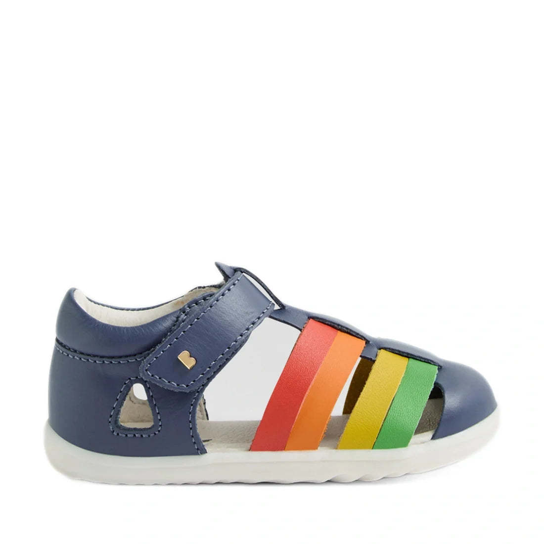 A navy blue Bobux Step Up SU Toddlers Tidal Vintage Indigo Blue Closed Toe Sandal with a white sole and rainbow-colored straps (red, orange, yellow, green) across the top. This water-friendly leather sandal, inspired by the Bobux Tidal First Walking Sanda