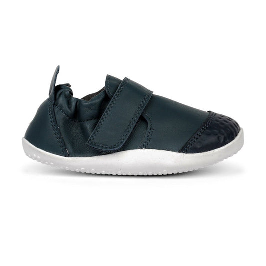 The Bobux Explorer Go First Walking Trainer Navy 501012B is a small, navy baby shoe with a white rubber sole, flexible design, hook-and-loop strap, elastic ankle for secure fit, and reinforced toe—perfect as first walking shoes., 9420062080245, 9420062080