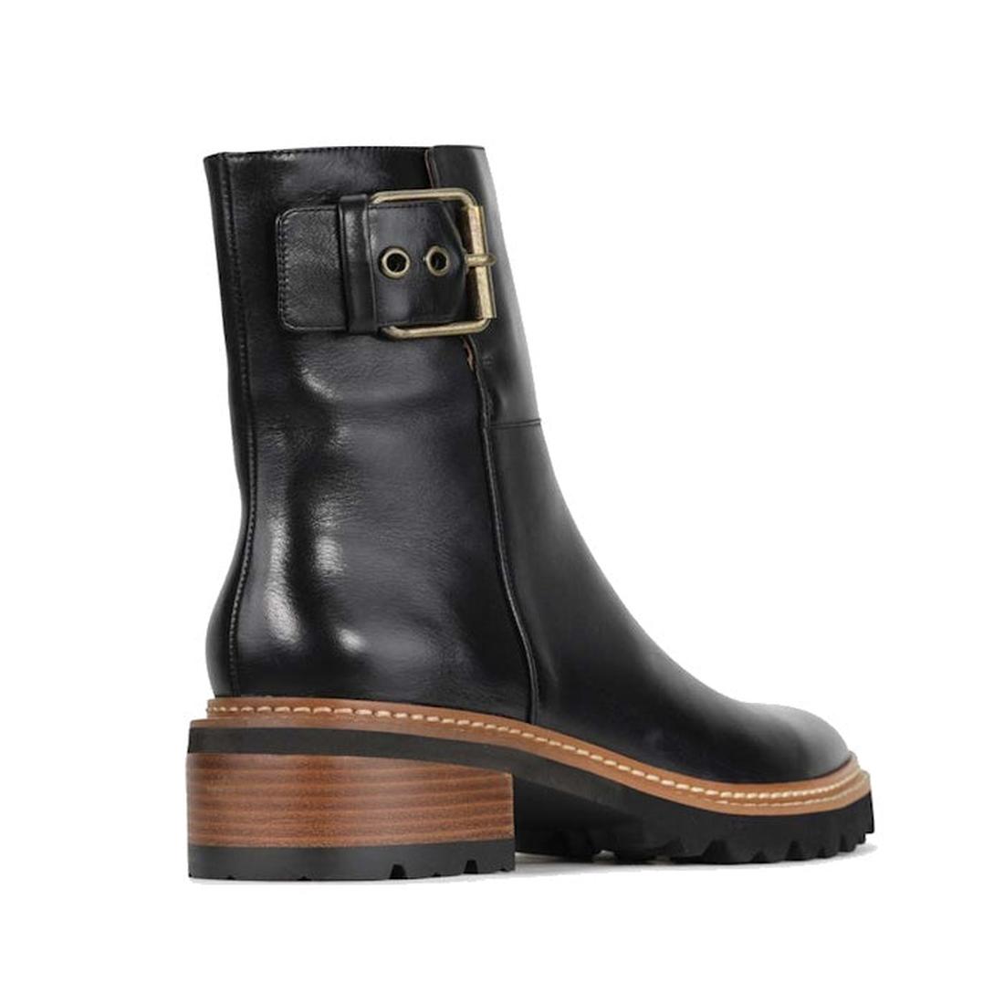 The EOS Lineman Black Womens Leather Boot features a cashmere leather upper, brown stacked block heel, lug sole, visible white stitching, and a decorative side buckle strap near the top—an elevated take on combat style boots.