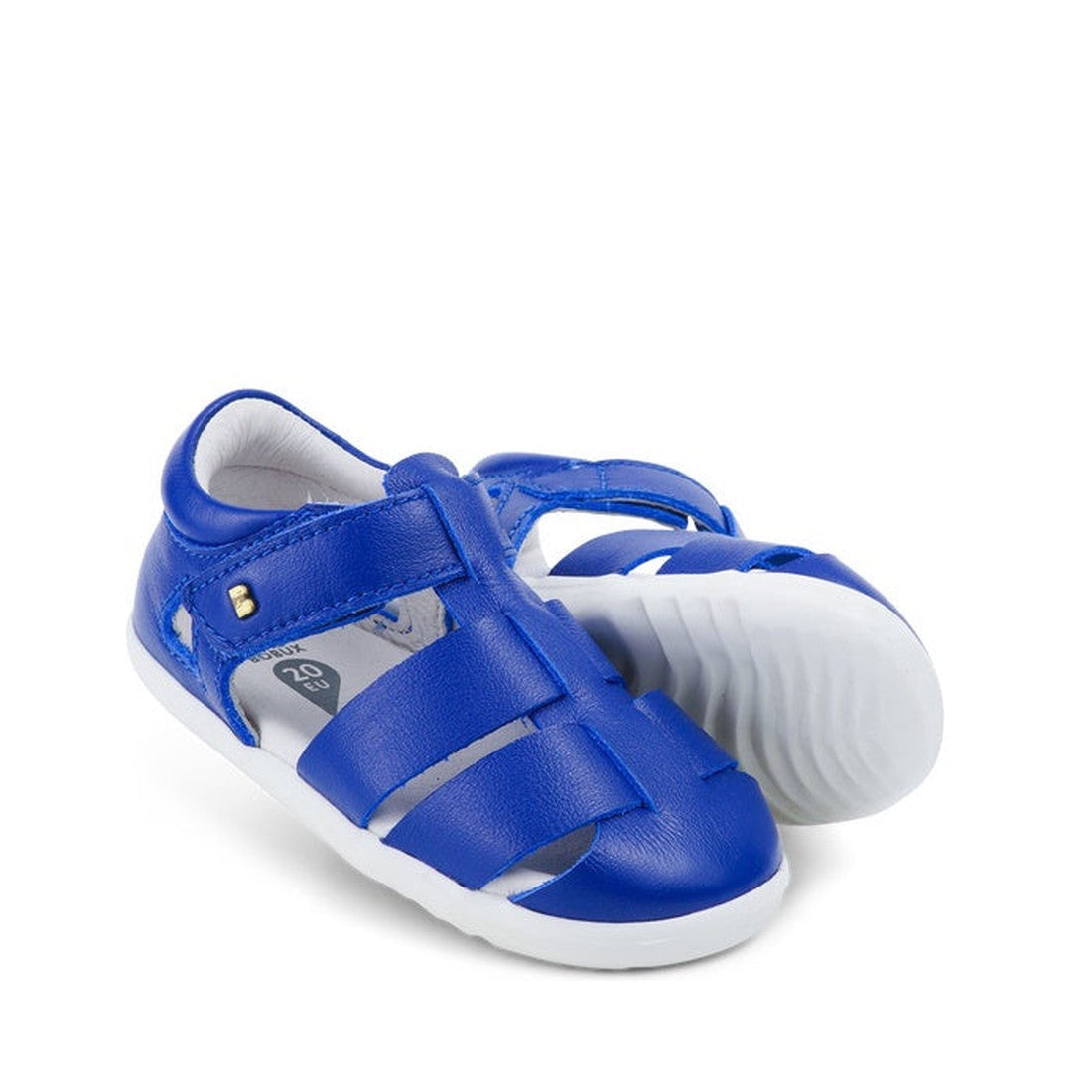 The Bobux Step Up US Tidal Blueberry Closed Toe Sandal 732501 features blue closed-toe toddler sandals with white soles, a closed heel, and Velcro strap—ideal as first walker shoes—shown against a white background.