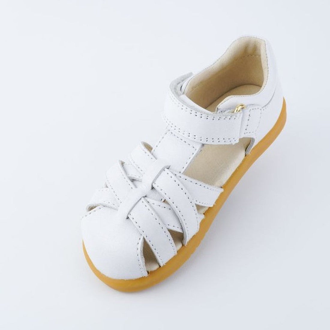The Bobux iwalk Cross Jump Sandal White Closed Toe 636706 is a children's white leather sandal with a closed toe, Velcro fastening, and tan rubber sole, shown on a plain white background., 9420062083949, 9420062083956, 9420062083963, 9420062083970, 942006