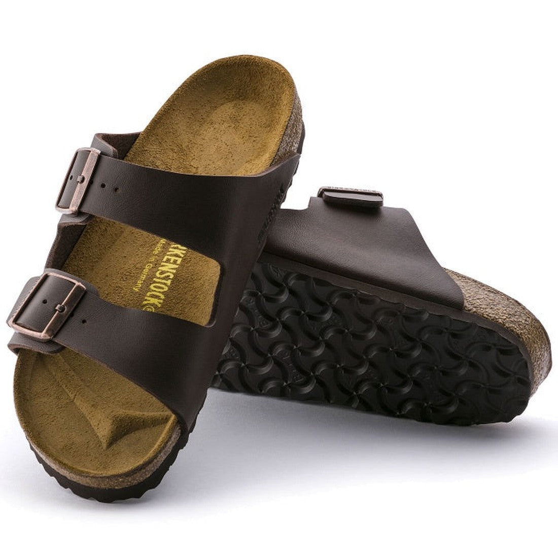 a pair of Birkenstock Arizona Smooth Leather Dark Brown Narrow Width with double straps, one over the foot and one over the toes with buckle adjustment. Staps are linked at the sides of the foot. Leather thick straps and a suede leather footbed. Also show