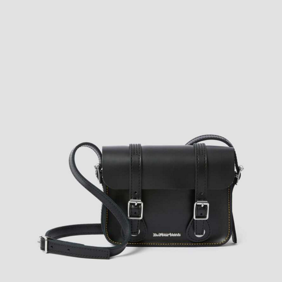 The Dr Martens - Doc Leather Cross Body Black Leather Satchel 7 inch is a sturdy black mini bag with silver buckles and contrast stitching.  ksnz