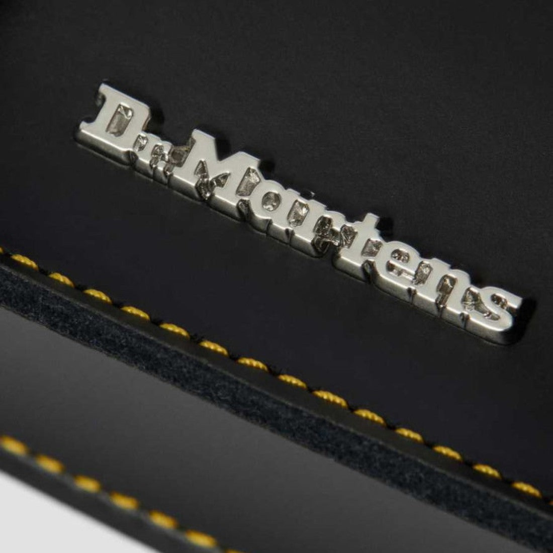 Warm close-up of the Dr. Martens Kids' Black Leather Satchel, showing sturdy yellow stitching and classic logo on durable leather.  ksnz, 190665191974