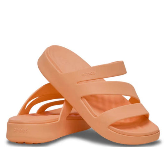 A pair of Crocs Women's Getaway Strappy Slide Sandals in Electric Sunstone Orange, featuring three straps and a thick, contoured sole with Free Feel Technology. One sandal stands upright; the other is tilted and leaning against it.