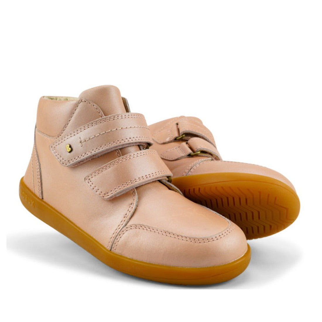 The Bobux Kids Plus KP Timber Boot Dusk Pearl Pink 832918 features smooth pink leather, double straps, brown rubber soles, and a high-top design for children, shown against a white background.