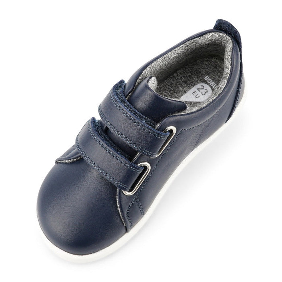The Bobux Iwalk Grass Court Navy Leather Trainer 633723J is a single kids’ casual shoe in navy blue with two velcro straps, a white sole, and gray lining, shown angled on a white background., 9420075792548, 9420075791404, 9420075792227, 9420075792784, 942