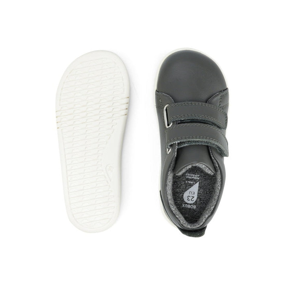 The Bobux Iwalk Grass Court Smoke Grey Leather Trainer 633702 kids sneakers feature gray uppers with white soles; one shoe displays the textured sole, while the other highlights Velcro straps and size label. Ideal casual footwear for kids., 9420068517974,