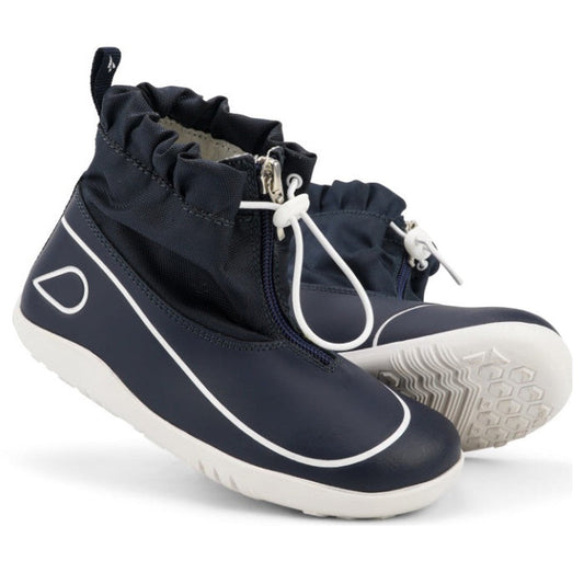 The Bobux Kid+ Splash Boot Waterproof Navy 839004 is a pair of kids' navy slip-on boots with white soles, white trim, elastic drawstring ankle closures, and textured tread for extra grip.