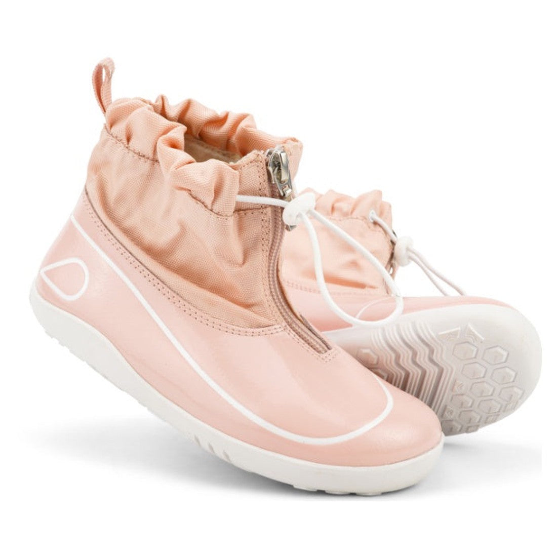 The Bobux Kid+ Splash Boot Waterproof Seashell Pink 839011 is a light pink, high-top kids’ shoe with white soles, zip closures, elastic drawstrings at the ankles, sporty design with white accents, and a hexagonal outsole pattern.