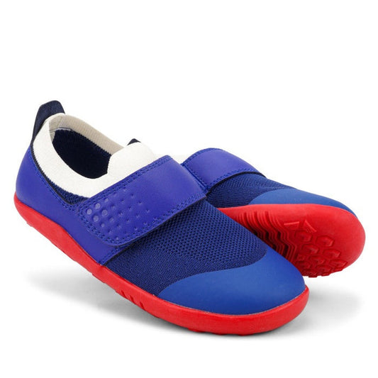 A pair of Bobux Kid+ Lo Dimension III Blueberry 838605 shoes on clearance, feature blue mesh uppers, wide blue straps, white lining, and bright red soles—flexible performance shoes for active kids. One stands upright; the other shows its sole.