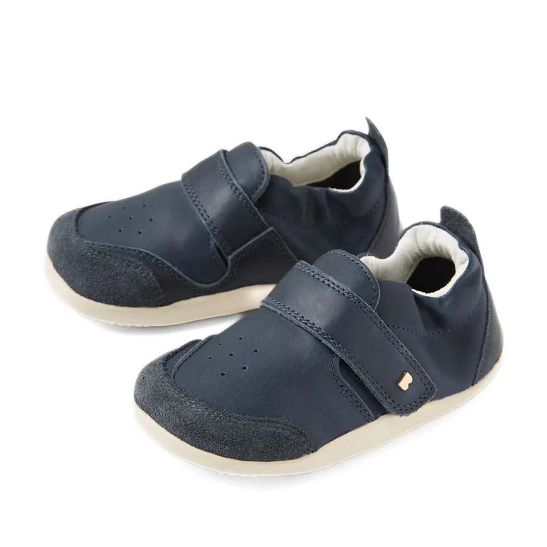 A pair of Bobux XP Explorer Ripple First Walker shoes in navy, featuring beige soles, Velcro straps, and soft suede toe caps. These flexible-soled toddler shoes are perfect for first walkers and are displayed on a white background.