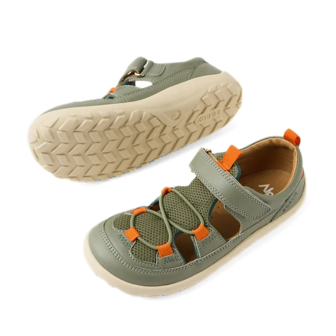 A pair of Bobux Kid+ KP Rocky Leather Closed Toe Sandal Vetiver Green Barefoot for kids features green and orange leather with white soles. One sandal stands upright, displaying the top and side view, while the other is flipped over to reveal the tread pa