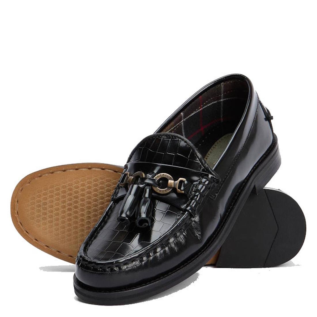 The Barbour Jen Black Womens Croc Tassel Leather Loafer features a shiny croc-embossed finish, gold-toned hardware, and tassels. One loafer stands upright; the other lies on its side, showing a light brown sole with a hexagonal pattern