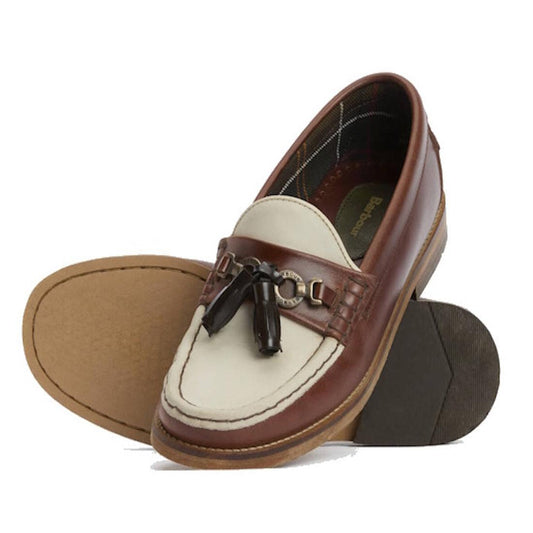 The Barbour Jen Mahogany & Beige Women's Tassel Leather Loafer features cream and brown leather, tassel and metal details on the front, plus tan rubber soles—one shoe is upright while the other shows its sole.,