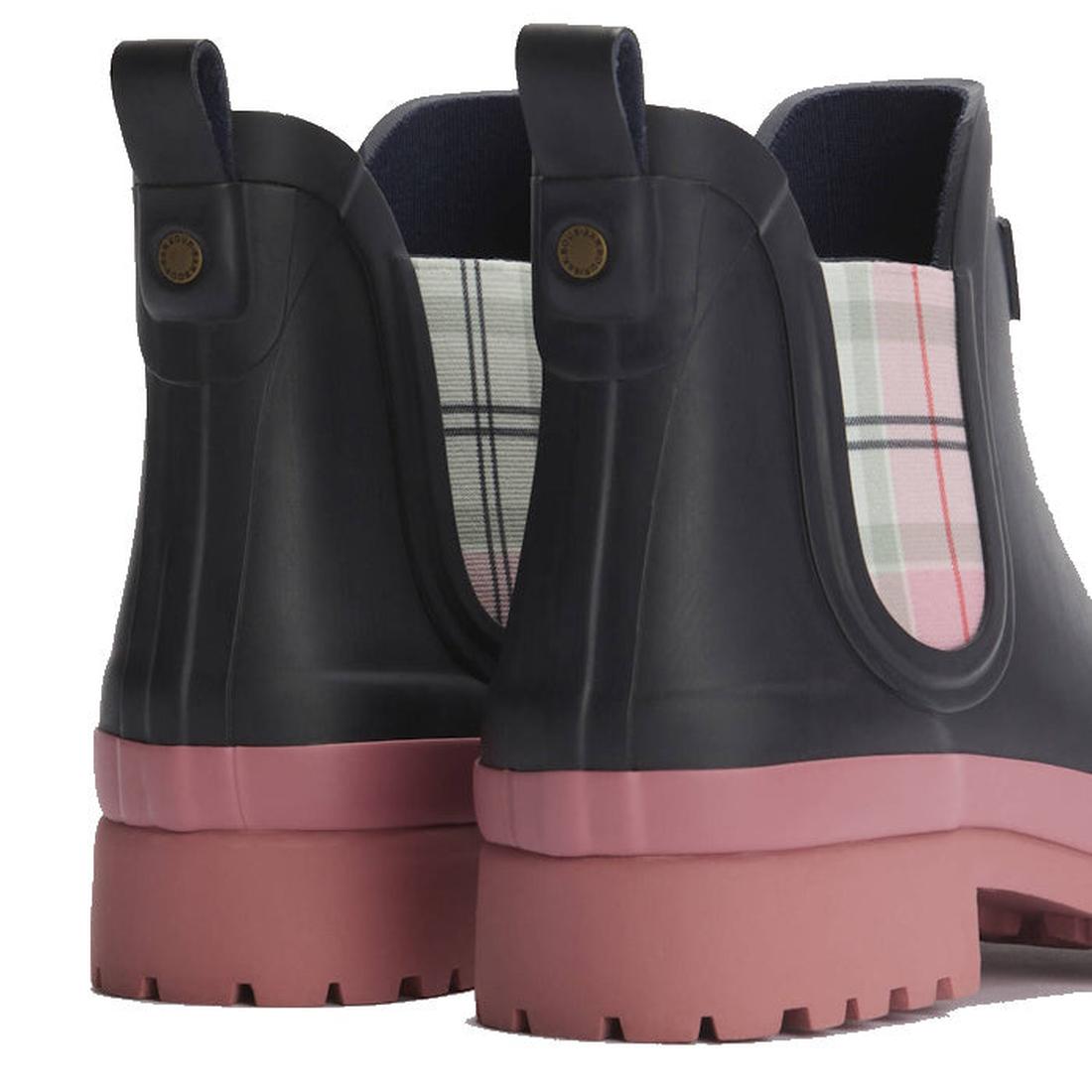 A close-up of the Barbour Mallow Navy Cherry Blossom Chelsea Women's Wellington Rainboots shows black uppers, pink soles, and plaid panels in white, pink, and green—ideal weatherproof boots for rainy days., 5063669170908, 5063669170915, 5063669170922, 506