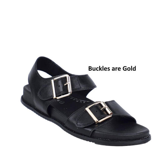 The Bay Lane Zeus Black Womens Leather Sandal with Back Strap features double black leather buckle straps with gold-colored buckles, an open toe, and a flat sole. Text beside the sandal reads: Buckles are Gold.