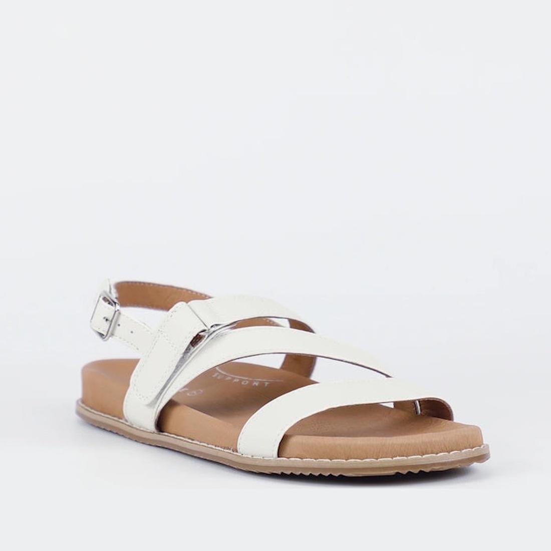 The Bay Lane Zorba Ice White Women's Leather Flat Sandal features a white strappy design, adjustable back strap, cushioned footbed, flat tan sole, and open toe, shown against a plain white background.