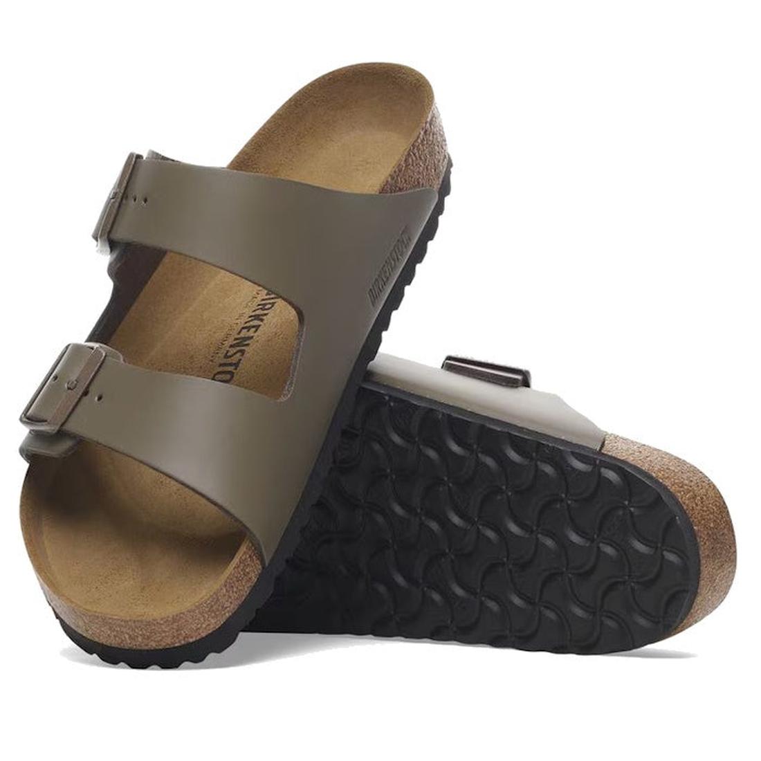 A pair of Birkenstock Arizona Concrete Grey smooth natural leather sandals (regular width) with two adjustable straps, anatomically shaped footbeds, and black textured rubber soles. One sandal is upright; the other is on its side showing the sole.