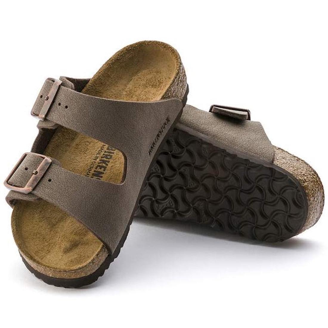 A pair of Birkenstock Kids Arizona Mocca Birkibuc Narrow Slides, featuring two buckled straps, contoured cork footbeds, and black textured soles. One slide is upright; the other is propped up to display the sole.