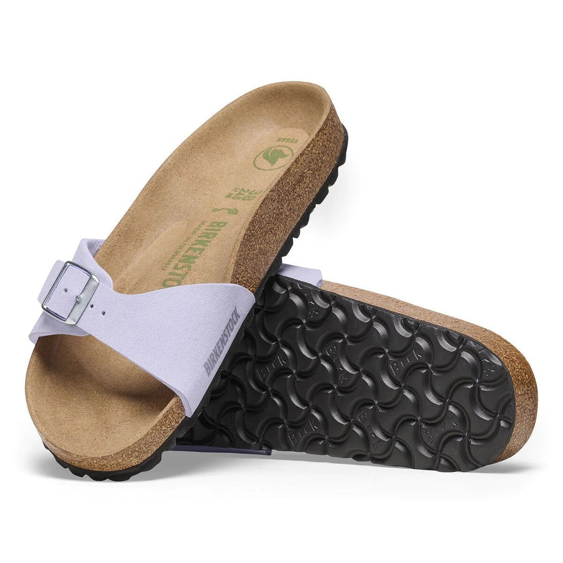 A pair of Birkenstock Madrid Women’s Vegan Slides in Purple Fog with anatomically shaped cork footbeds, black textured soles, and light purple straps with a silver buckle. One sandal stands upright while the other shows the sole.