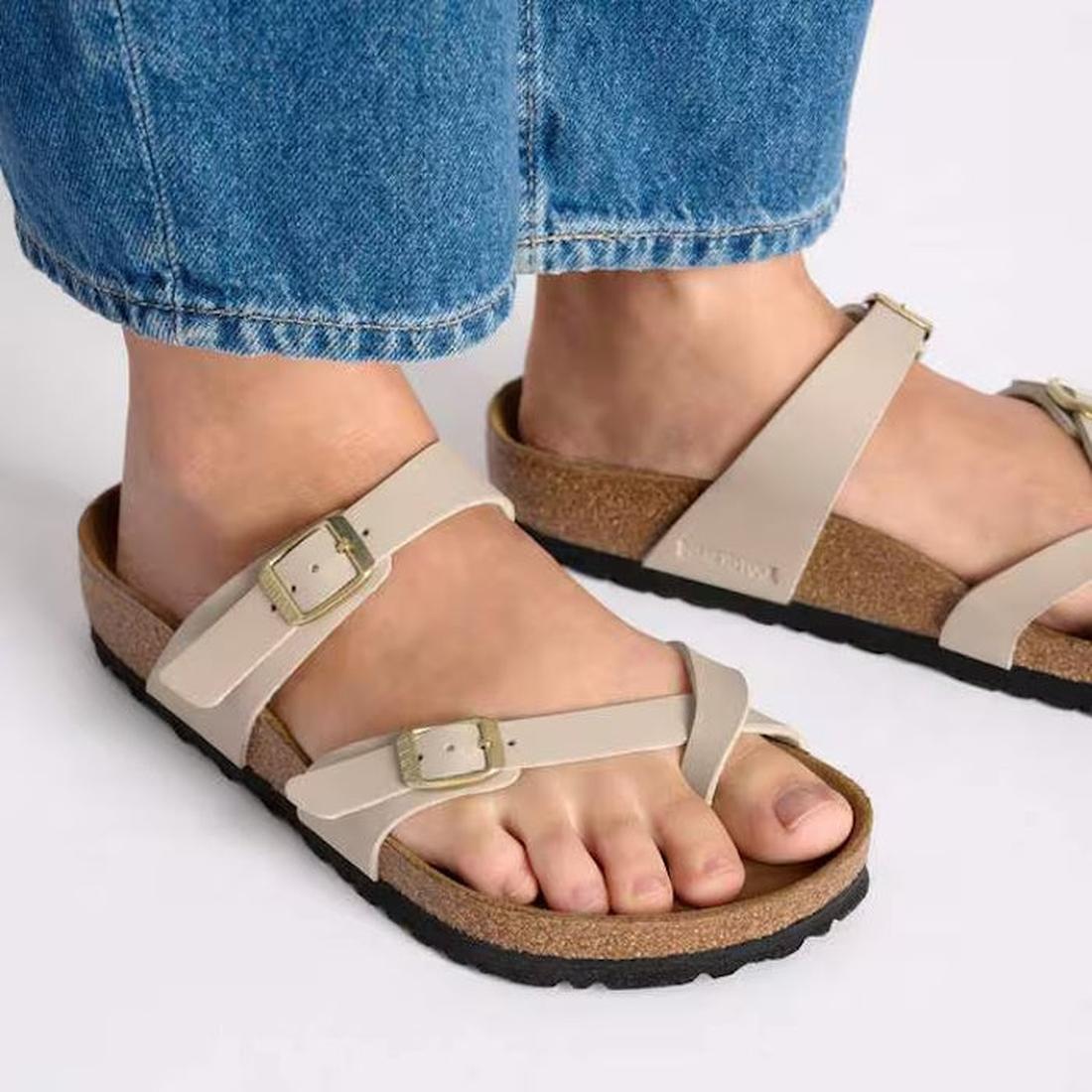A picture of a womens feet wearing blue denium jeans and Mayari Birkenstock toe loop sandals in sandcastle beige looking top down., 4067707169030,
4067707169078,
4067707169115,
4067707169153,, 49314, 49315, 4067707169030, 4067707169078, 4067707169115, 406, 49320, 49321
