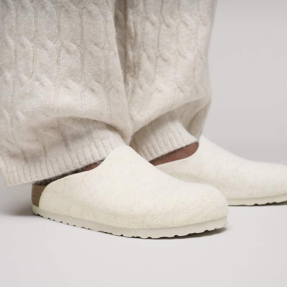 A person in textured cream pants and matching Birkenstock Amsterdam Felt Wool Clog Eggshell Off White (Regular Width) with cork-latex footbed, standing on a light surface., 51708, 51709, 4067707298440, 4067707298488, 4067707298525, 4067707298563, 51714, 5
