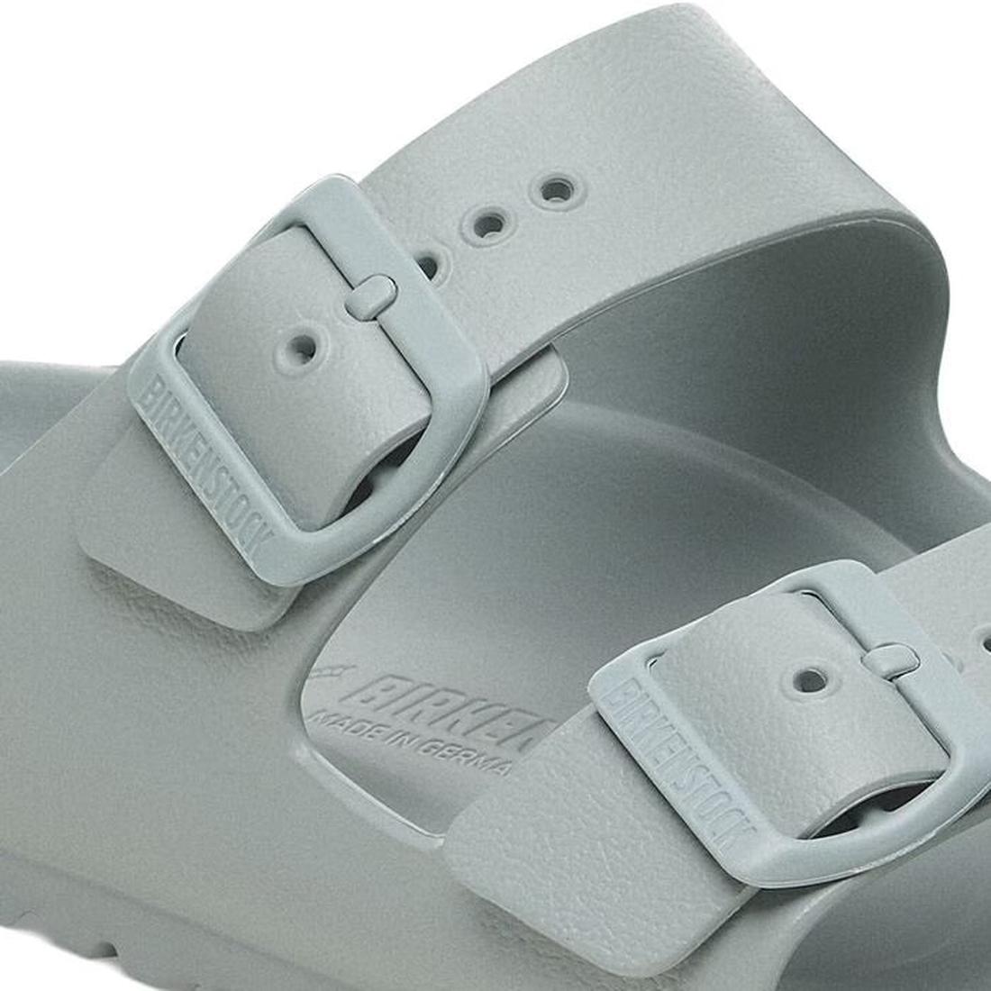 Close-up of a sage green Birkenstock Arizona EVA sandal in narrow width, featuring two adjustable straps with metal buckles, embossed branding, textured waterproof material, and part of its contoured footbed., 47527, 4067707110742, 4067707110780, 40677071