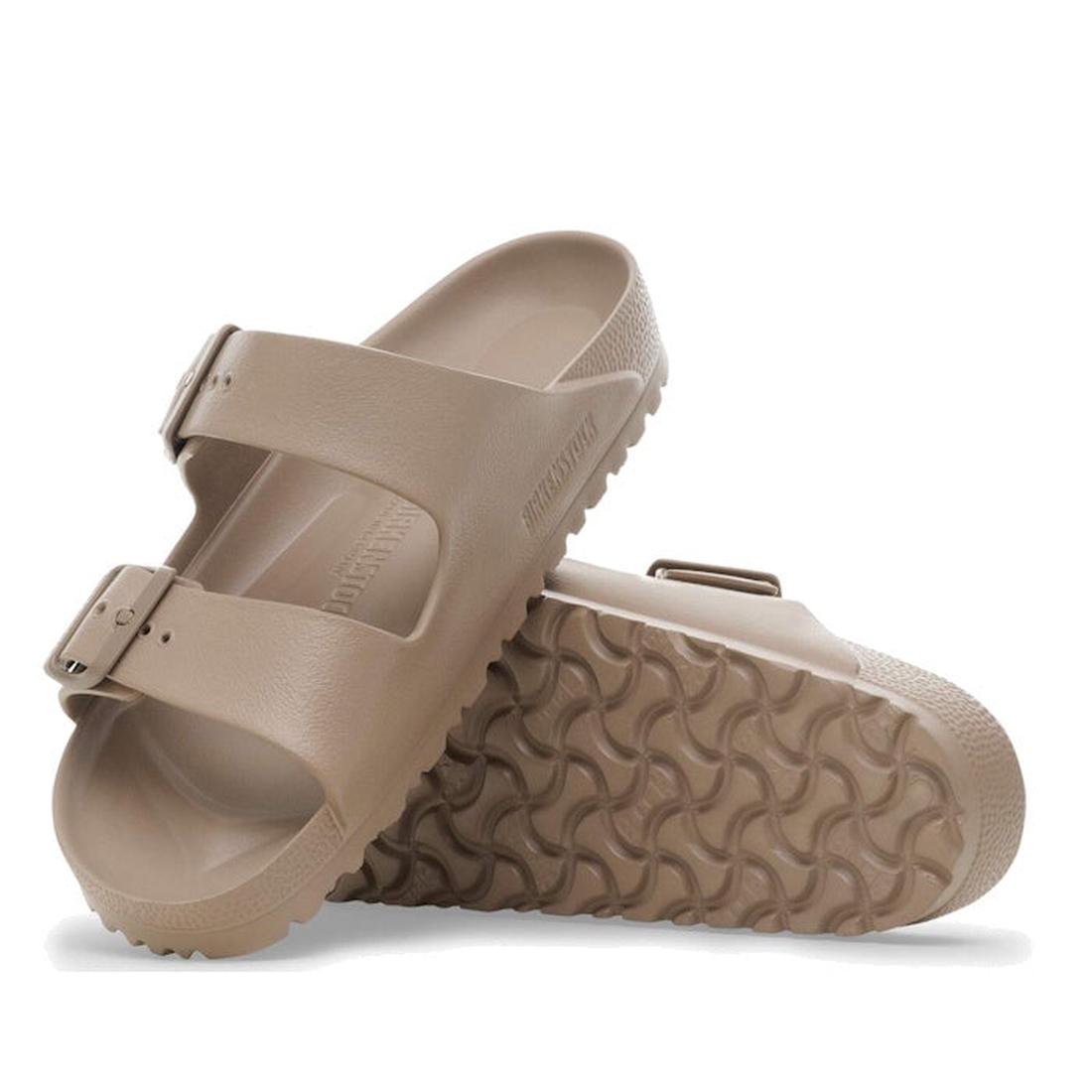A pair of Birkenstock Arizona EVA Grey Taupe Regular Fit sandals with two adjustable straps and textured, waterproof soles—one upright, the other tilted to showcase the wavy tread pattern.