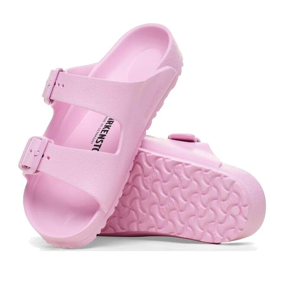 A pair of Birkenstock Kids EVA Fondant Pink Arizona Sandals (Narrow Width) featuring two adjustable straps and a textured sole. One sandal stands upright, the other lies on its side, showing their waterproof design.