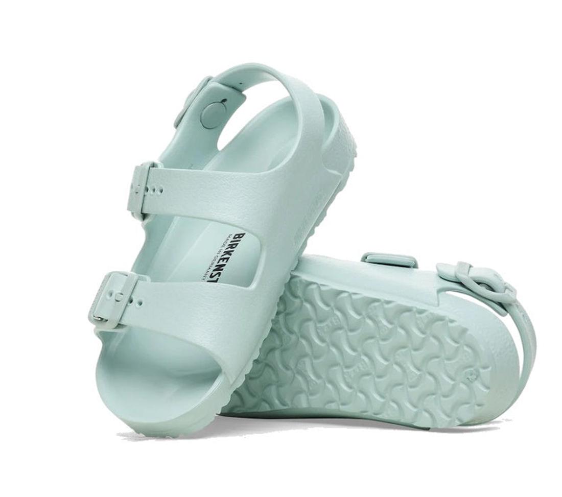 A pair of Birkenstocks Kids Surf Green Milano EVA Sandal Narrow Width: one waterproof sandal stands upright with the brand name visible on the insole, while the other lies on its side, showing the sole's tread pattern.