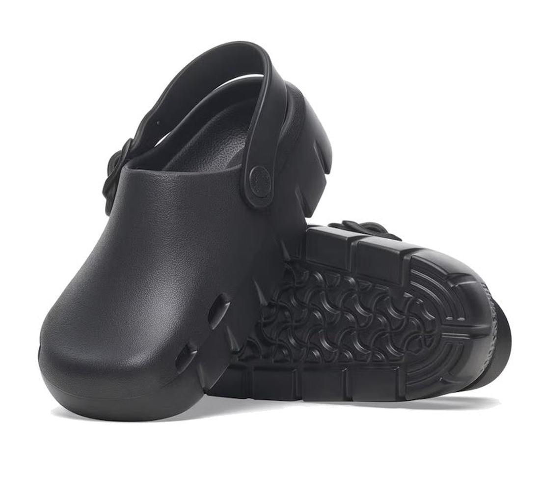 A pair of Birkenstock Kids EVA Black Birki-Flow Clog Sandals features a chunky sole, closed toe, adjustable back strap, and patterned tread—durable, water-friendly shoes ideal for any adventure. One sandal is upright; the other shows the sole.
