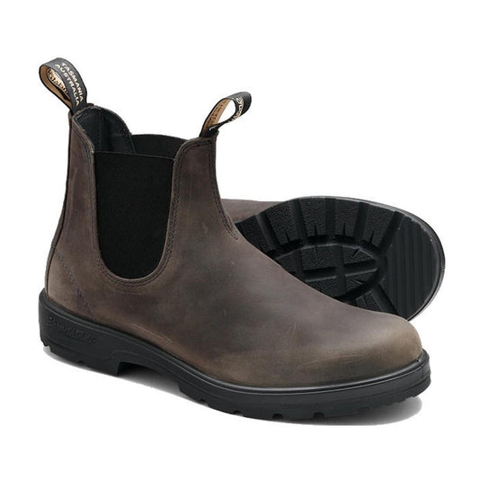 The Blundstone 2446 Chelsea Boot in Vintage Clay Brown features black elastic side panels, water-resistant leather, sturdy black rubber soles, and pull tabs for easy wearing. One boot stands upright while the other lies on its side.