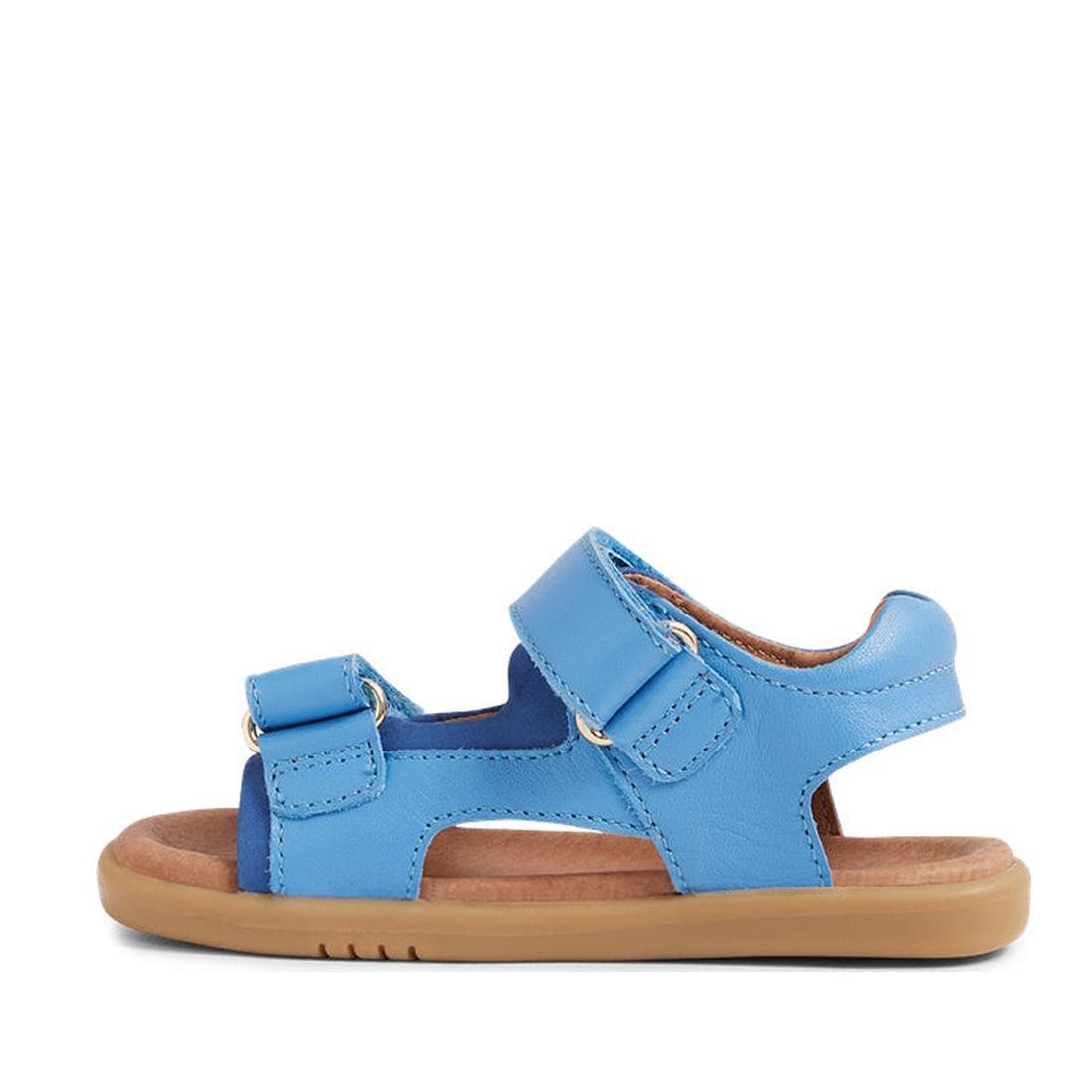 The Bobux IW Iwalk Strand Sandal in Azure Blue is a single toddler sandal with two adjustable straps, a cushioned brown sole, and an open toe. Made from washable material, it's shown in profile against a white background., 9420068556997, 9420068557000, 94
