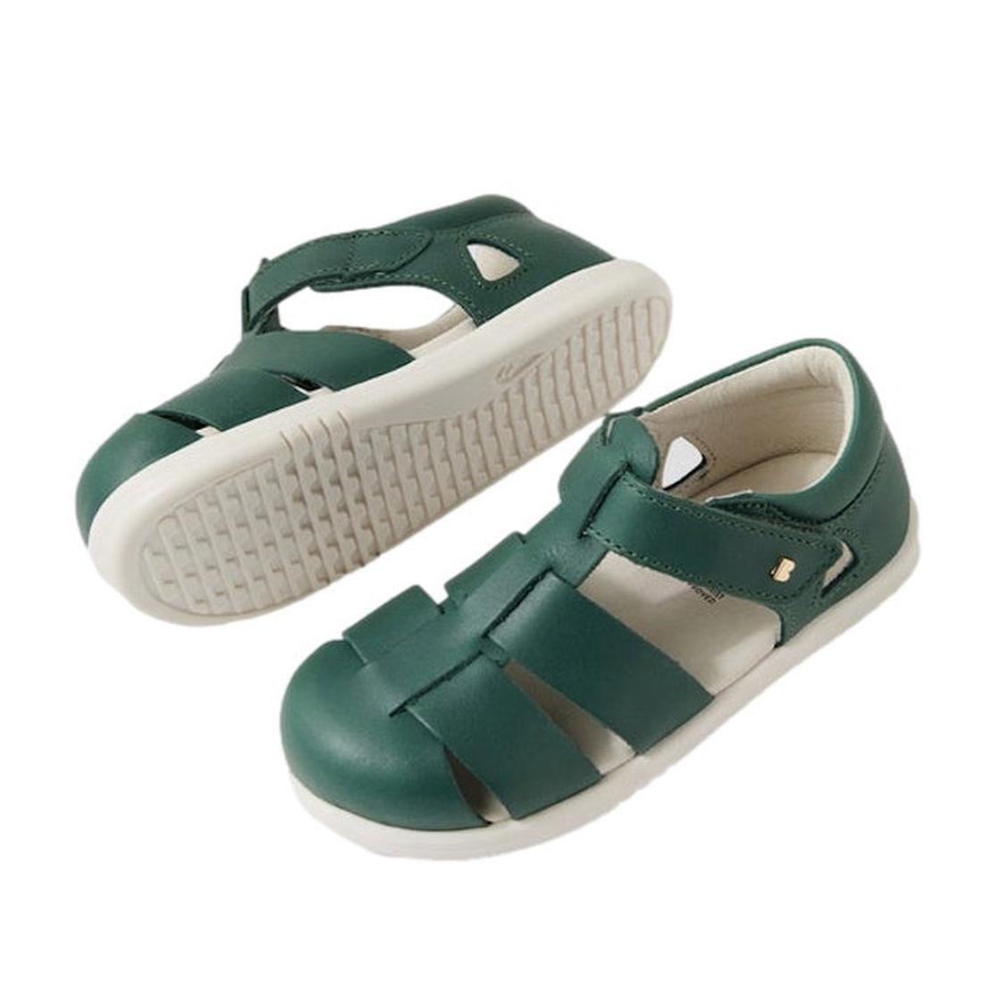A pair of Bobux Iwalk IW Quick Dry Tidal Closed Toe Sandal in Rainforest Green with white rubber soles. One sandal is upright, the other tilted to show the textured sole. Features a hook-and-loop strap and podiatrist endorsement.