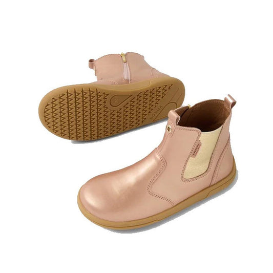 The Bobux KP Kids Plus Jodhpur 2 II Juniors Leather Boot in Rose Gold Metallic features pink leather, beige elastic side panels, tan rubber soles, and back pull tabs. Shown from the side and sole view against a white background.