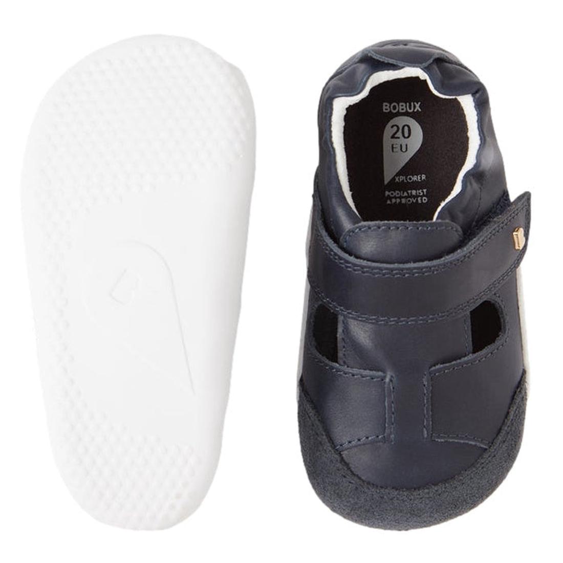 The Bobux XP Explorer Beau First Walker Sandal in Navy features a top view of a navy blue leather sandal with a Velcro strap and a side view displaying its flexible sole, ideal for toddlers taking their first steps., 9420068568808, 9420068568815, 94200685