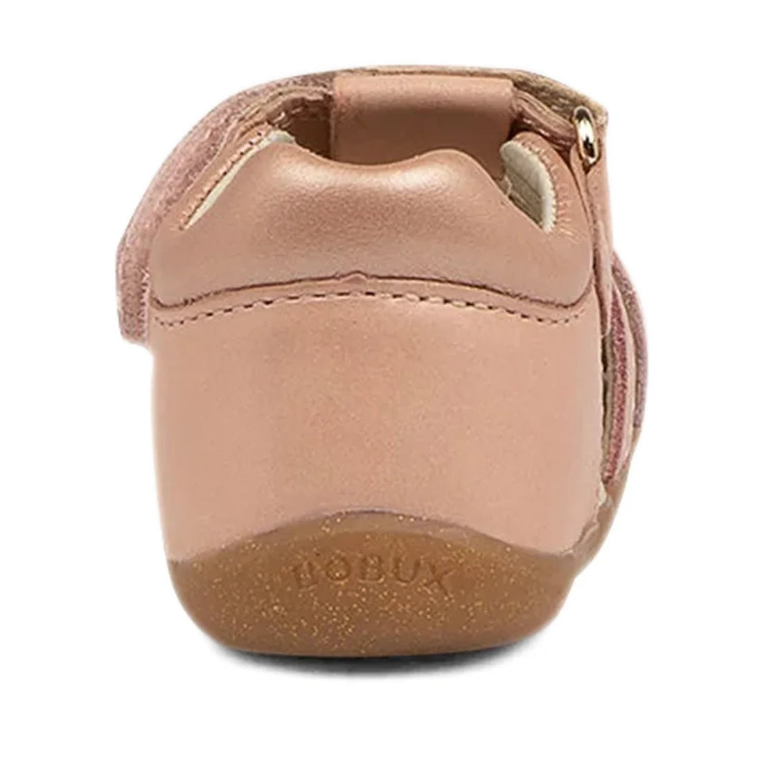 A dusk pearl pink leather Bobux Step Ups Cross Jump closed toe sandal seen from the back, featuring “BOBUX” embossed on the heel and a tan rubber sole—perfect as a stylish first walker for little ones taking their first steps.