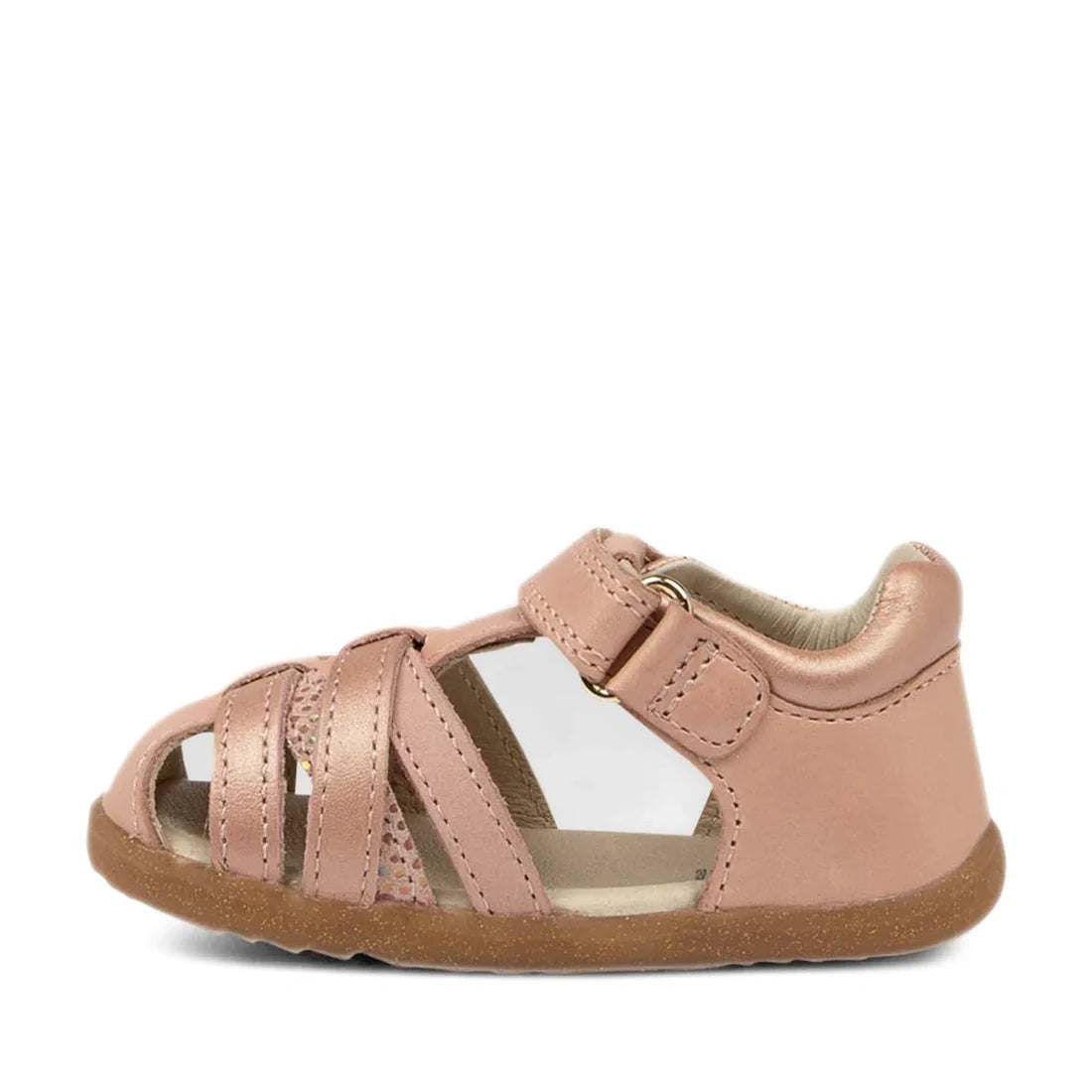 The Bobux Step Ups Cross Jump Dusk Pearl Pink Closed Toe Sandal is a pink toddler sandal featuring a closed heel, open toe, and multiple straps across the front. It has a Velcro ankle strap and a brown rubber sole.