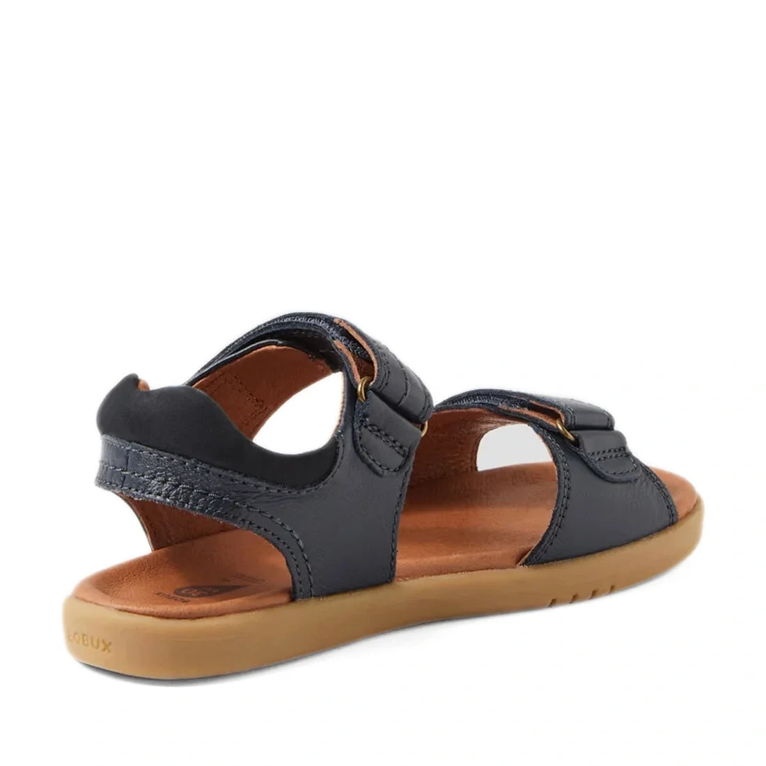A single Bobux Kid+ Plus Driftwood Navy Open Toe Sandal (style 833501AA) with a tan sole, open heel and toe, and two adjustable straps, shown from the side and slightly behind.