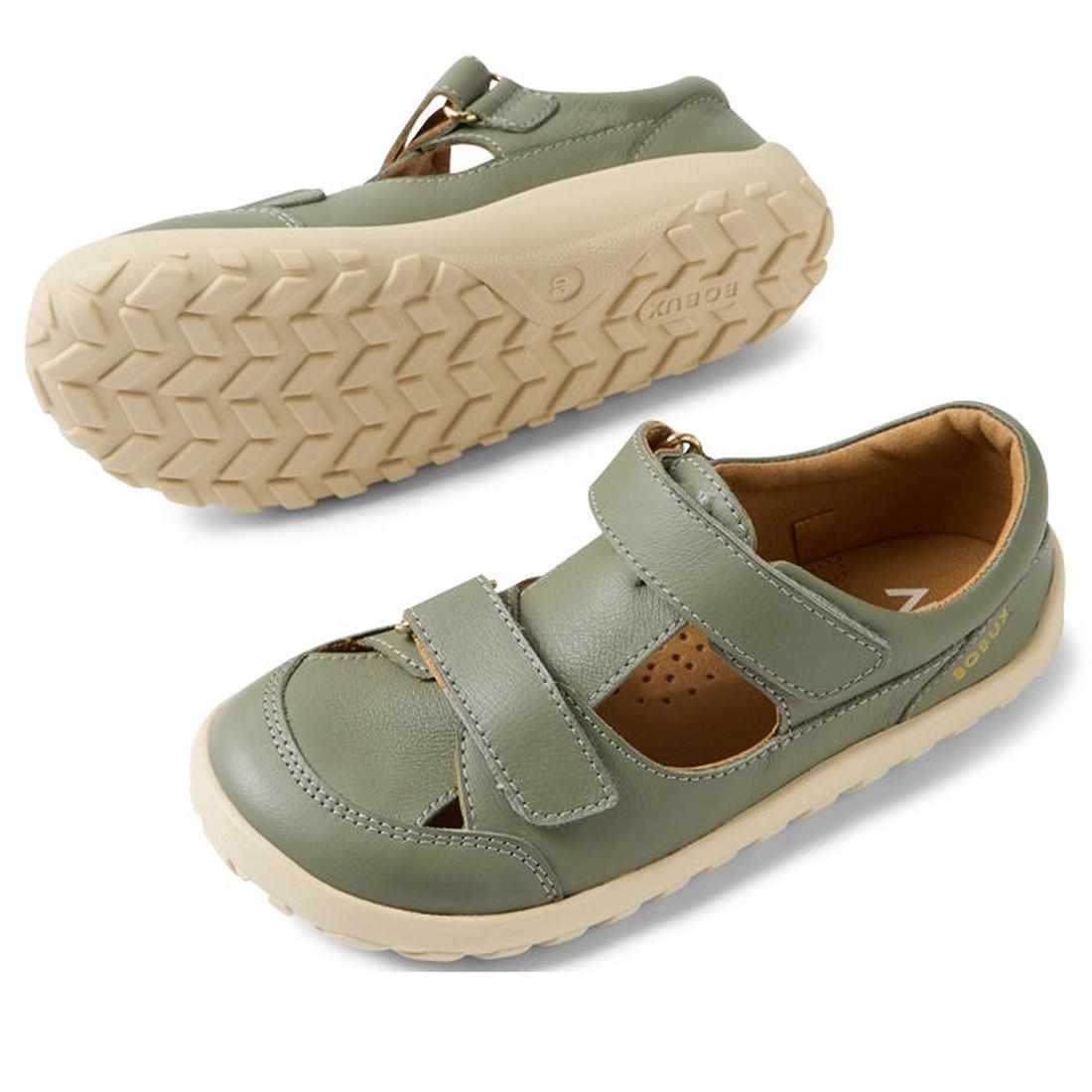 The Bobux Kid+ Troop Leather Closed Toe Sandal in Vetiver Green features sage leather, a wide toe box, beige rubber soles with tread, hook-and-loop straps, and perforated details—one is upright while the other shows the flexible sole., 9420074822802, 9420