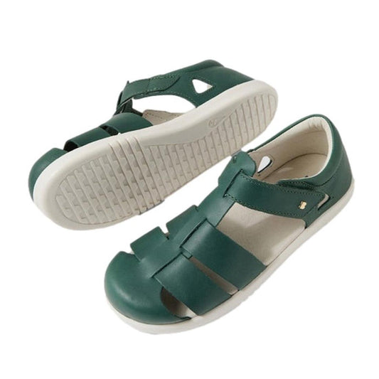 The Bobux Kids Plus KP Juniors Tidal Quick Dry Sandal in Rainforest Green is shown with one sandal upright showing the top and side view, and the other flipped to display the textured white sole. Both feature a strap fastening and closed-toe design.