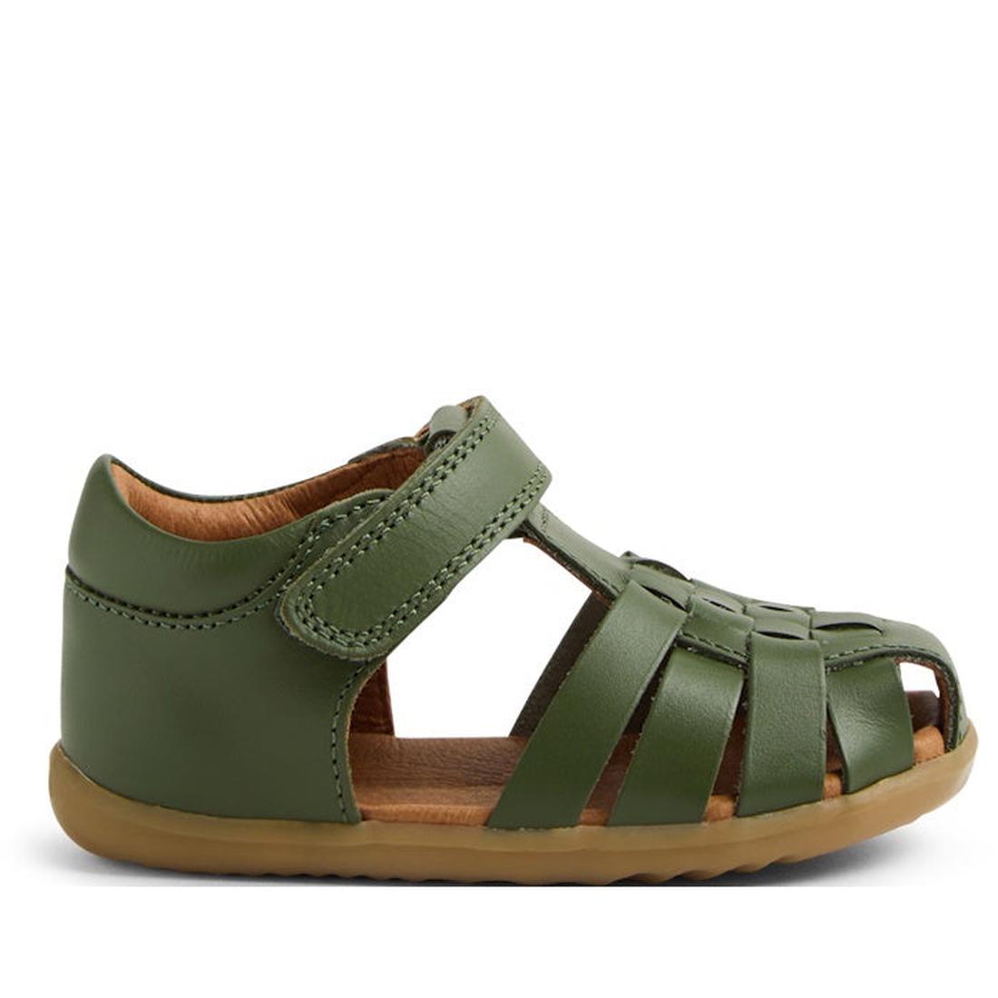 The Bobux Step Up Todders Sandal Harbor Closed Toe Bronze Green is a children's green leather sandal with a woven design, velcro strap, and flexible light brown sole—perfect for first walkers. Side view shown on white background.