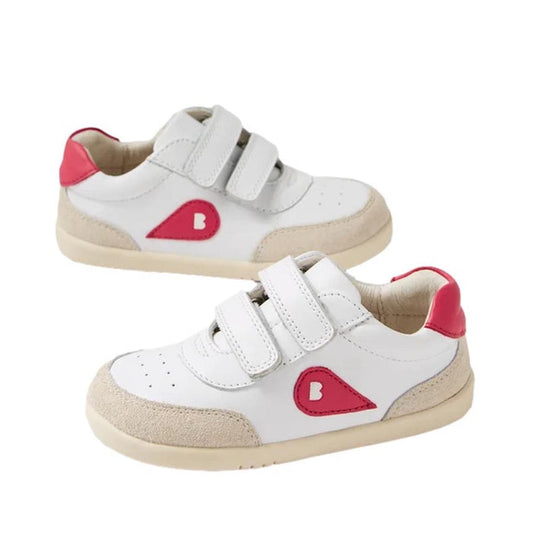 The Bobux Kids IWalk IW Champ Radiant Raspberry Sneaker 650506 features white uppers, beige soles, pink heel accents, two adjustable straps, and a pink teardrop design with a white "B" on the sides.